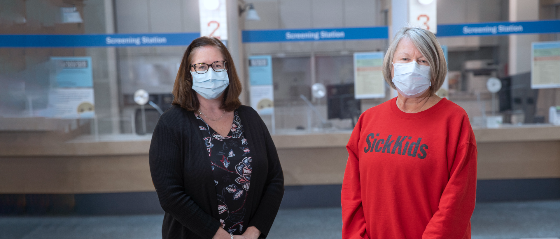 Stephanie Gracon-Lappan and Jane Ciordas-Lowes in masks. They are standing in front of the hospital screening stations.
