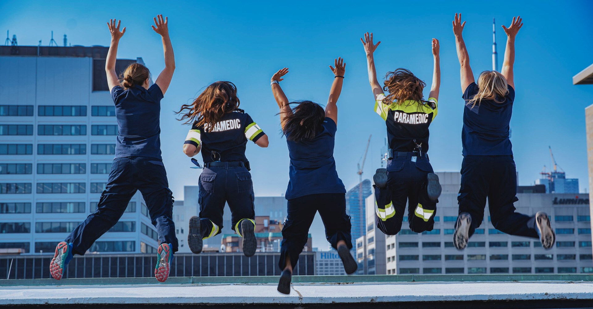 ACTS team members jumping in the air in unison on top of the SickKids helipad.